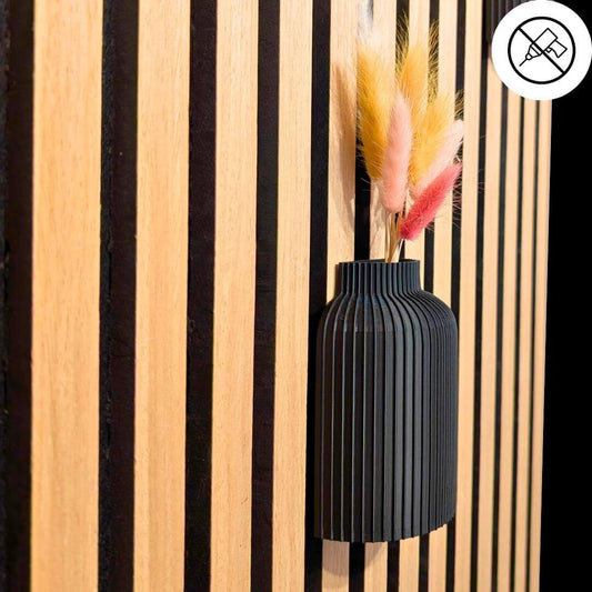 Hauptfoto: Schwarze 3D-gedruckte Wandvase für Akustikpaneele, Montage ohne Bohren (mit Symbol), dekoriert mit bunten Trockenblumen vor hellen Holzlamellen – Design von Mondhäuschen.