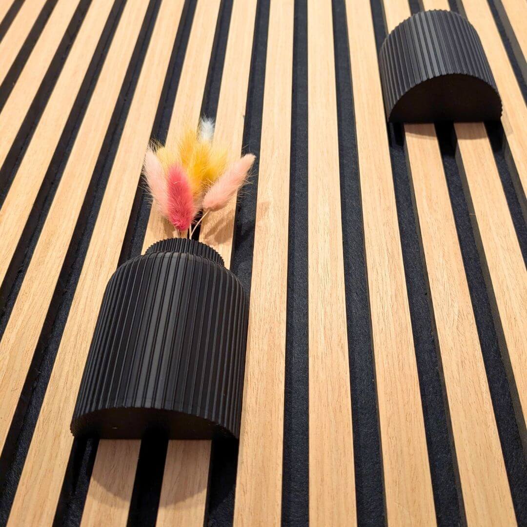 Seitenansicht der Wandvasen am Akustikpaneel: Fokus auf die gerillte 3D-Druck-Struktur und die perfekte Passform zwischen den Holzlamellen, Montage ganz ohne Kleben.