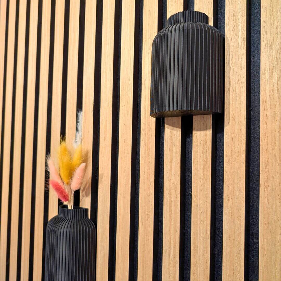 Schräge Ansicht der Wandvasen-Halterung am Akustikpaneel: Zeigt das schlanke Design und wie sicher die Vase ohne Bohren oder Kleben zwischen den Lamellen sitzt.