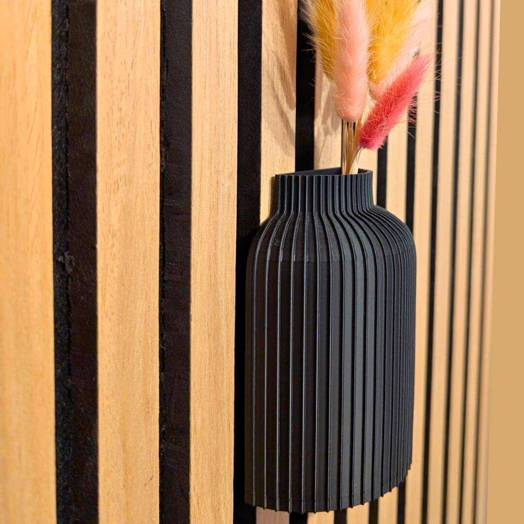 Detailaufnahme der mattschwarzen Vasenoberfläche: Die feine Rillenstruktur des 3D-Drucks und der nahtlose Übergang zum Akustikpaneel betonen das moderne Design ohne Bohren.